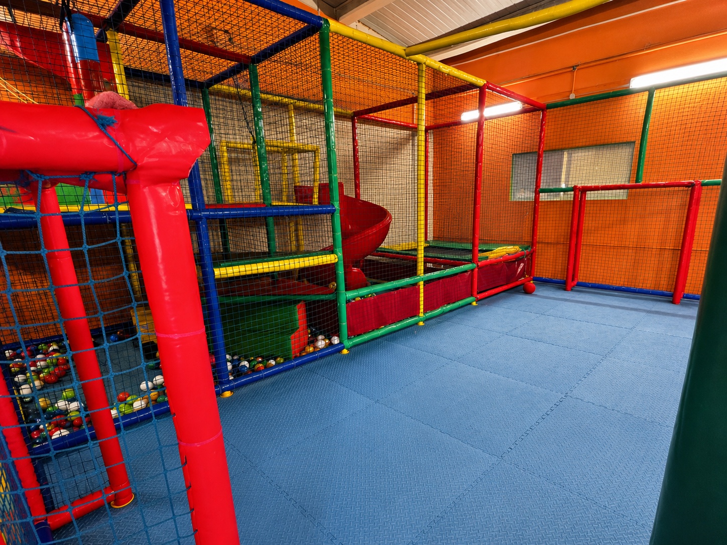 Zona infantil real con parque de bolas, tobogán y pista